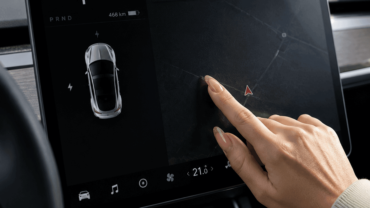 Driver touching an electric vehicle touchscreen with long nails, showing potential daily wear and scratch risks.